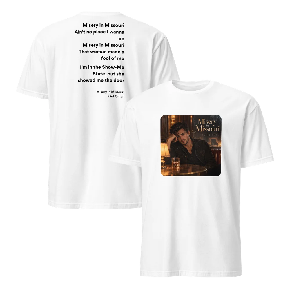 White Misery in Missouri lyric T-shirt shown front and back. The front prints the single art: a man in a dark jacket leaning on his hand at a bar table with a glass of whiskey and a lamp. The back prints chorus lyrics ending “she showed me the door” above the song title.